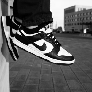Stylish black and white sneakers resting against an urban wall in a grayscale setting.